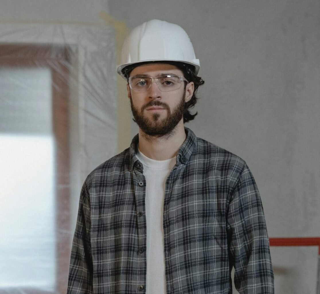 Adult male construction worker holding blueprints in an indoor renovation site.