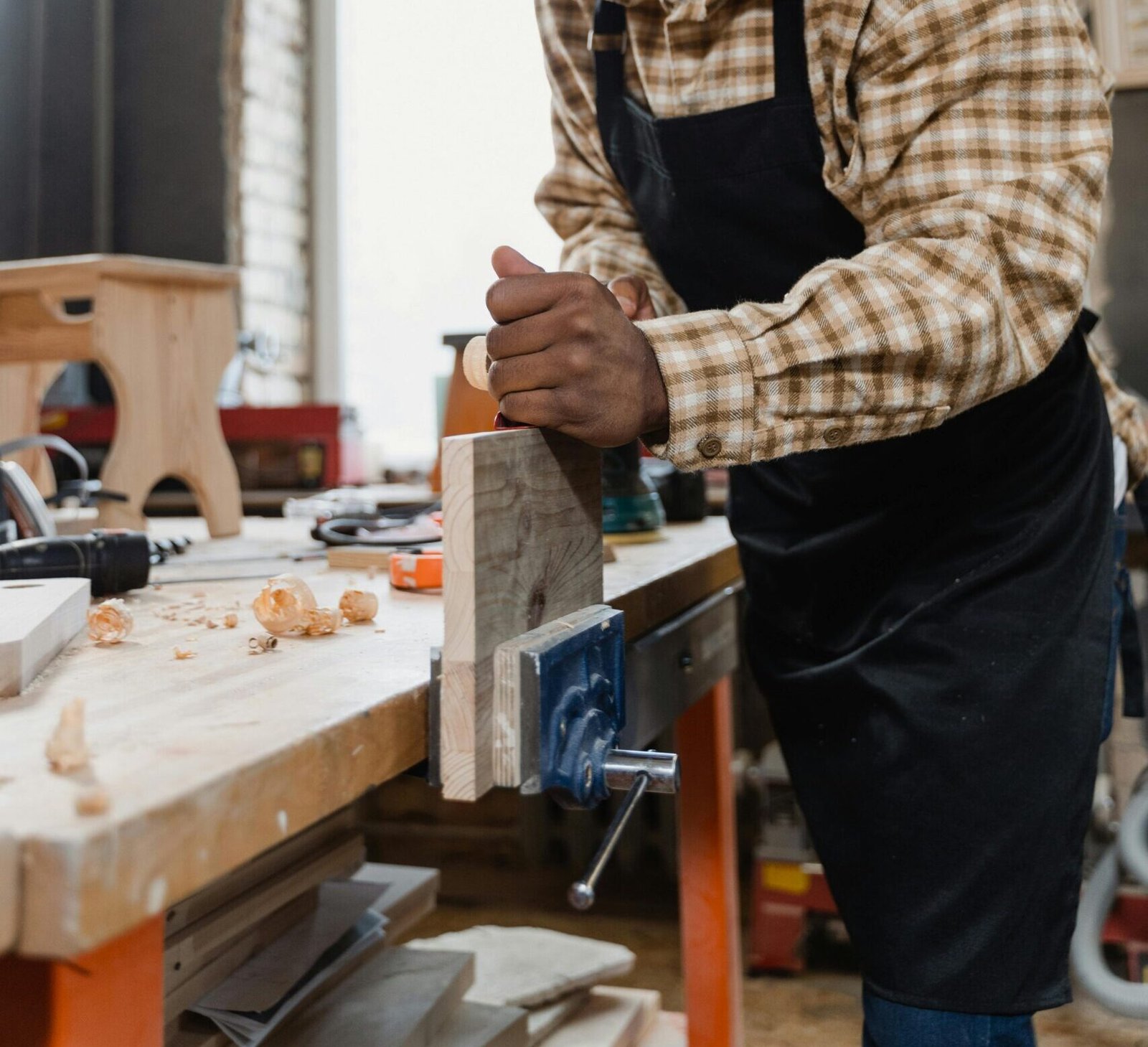 A craftsman focused on woodworking in a well-equipped workshop, creating wooden furniture pieces.